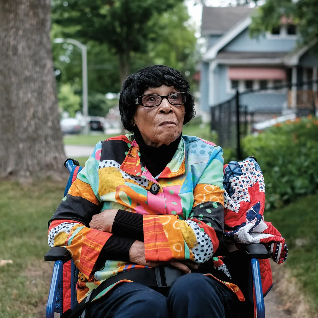a woman in a colorful jackets sits for a portrait outside