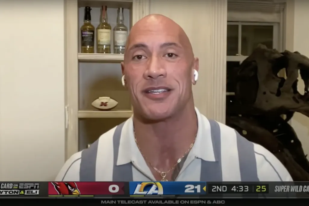 An image of Dwayne "The Rock" Johnson in a virtual call for ESPN's "ManningCast" show. Behind the actor is a T.rex skull.