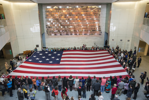 Museum visitors participate in a flag folding while singing (or humming) the anthem (NMAH)