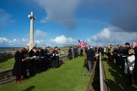 As we gathered at the graveyard, facing the sea and a memorial to the deceased, rain clouds parted, and the crowd was moved by the appearance of a rainbow. 