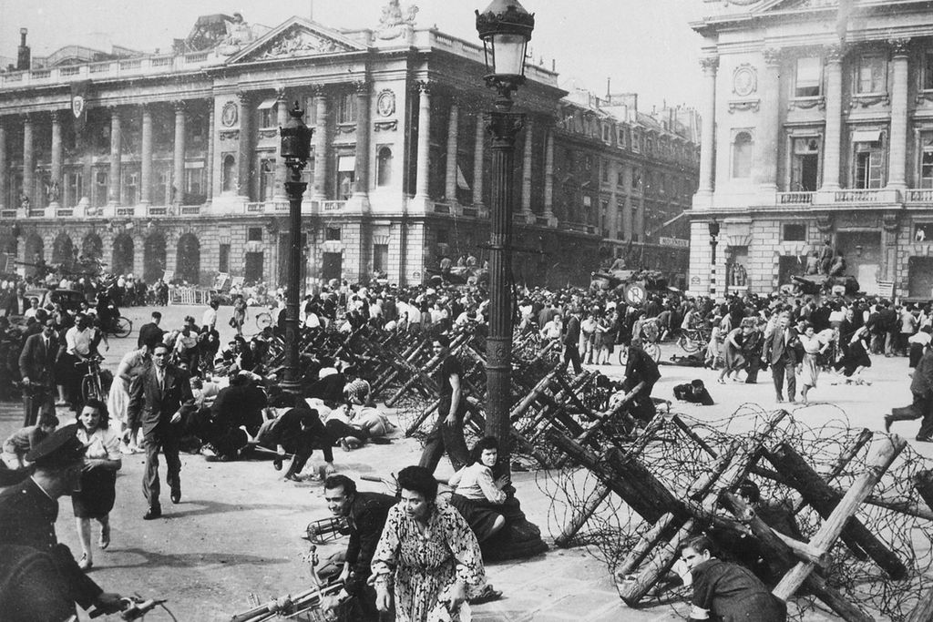 Crowds of Parisians celebrating the entry of Allied troops into Paris scatter for cover as a sniper fires from a building on the Place de la Concorde.
