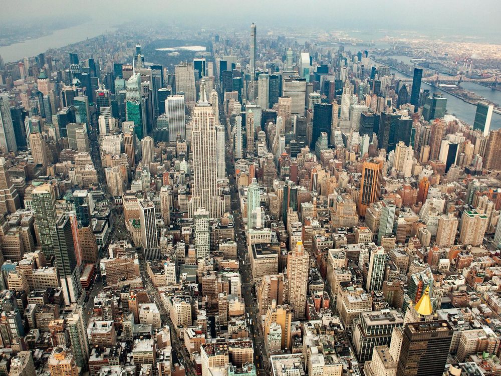 An aerial photograph of New York City. There are endless rows of skyscrapers and shiny buildings, stretching back to the horizon. 
