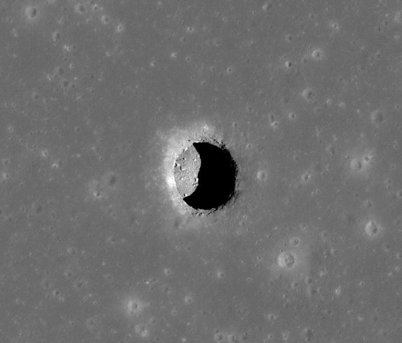 A grey image of a pit on the surface of the moon