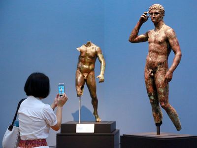 A reporter photographs "Statue of a Victorious Youth" on display at the J. Paul Getty Museum.