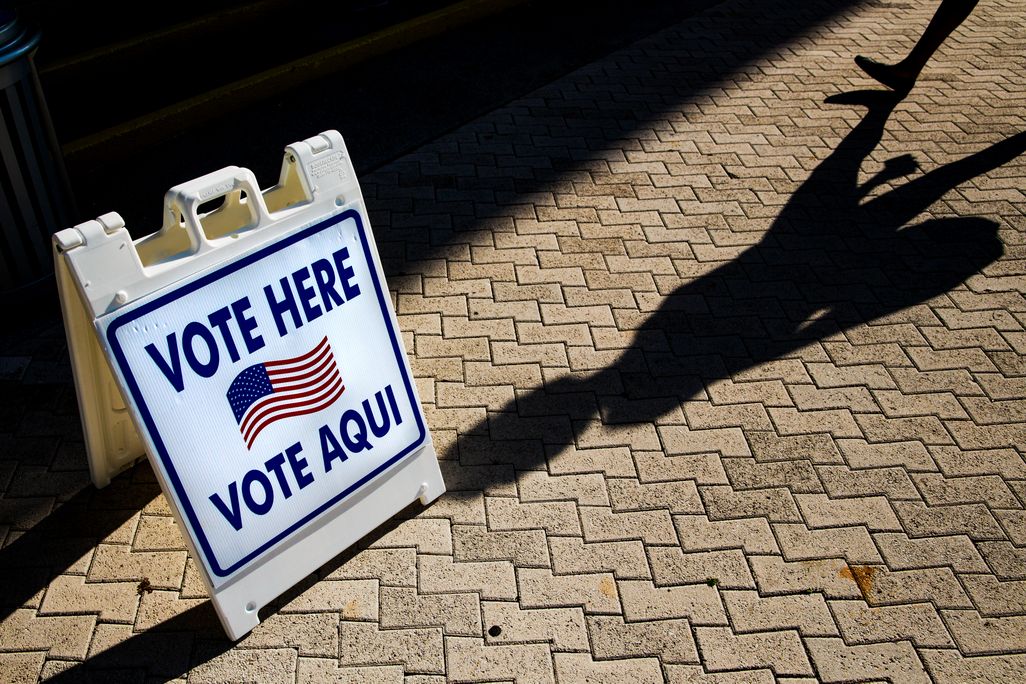 sign saying "vote here" and "vote aqui"