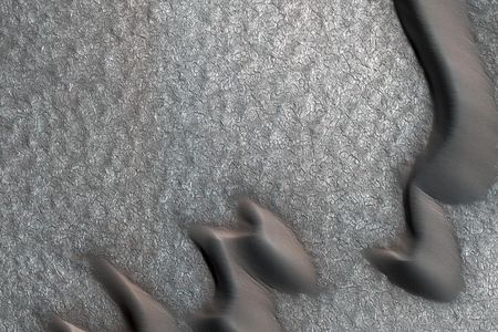 This image shows curved sand dunes but also a strange pattern of boulder piles on the landscape of Mars.