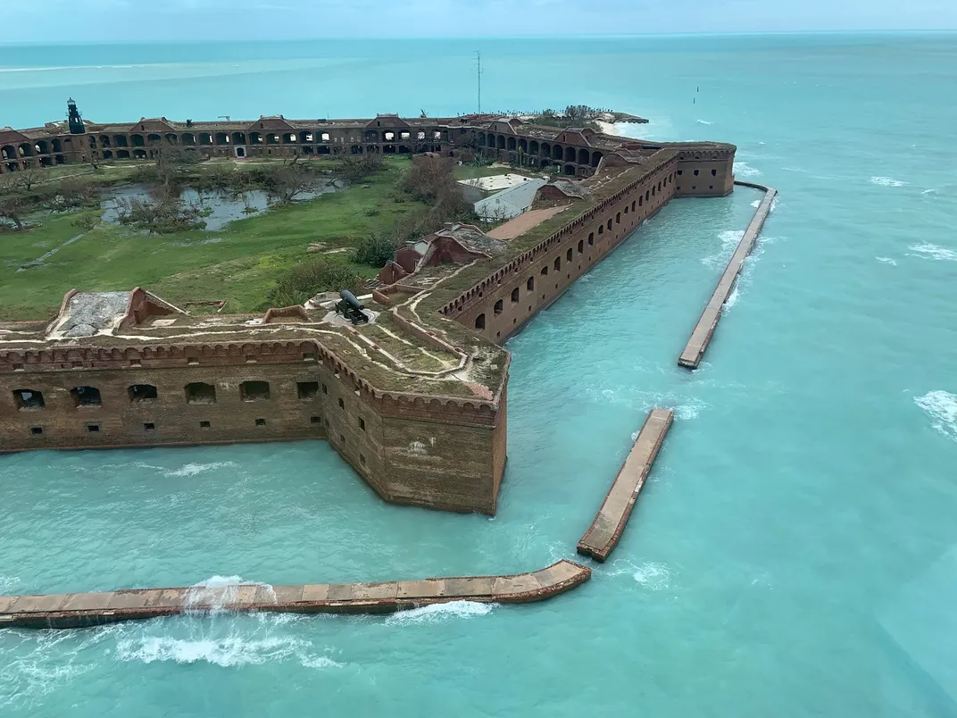 A brick building on an island surrounded by bright blue water