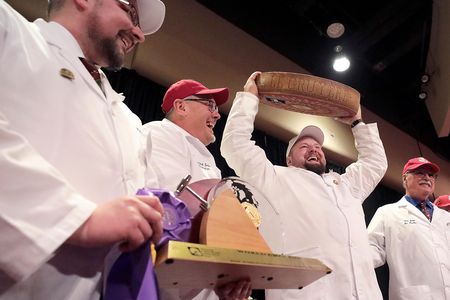 Christian Schmutz of the Swiss Cheesemakers Association hoists a 77-pound wheel of gruyère, which won the World Championship Cheese Contest last week.