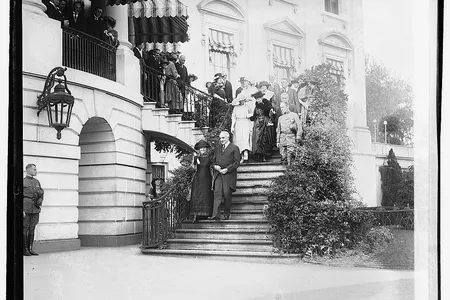 Marie Curie and President Warren Harding walk down the White House steps arm in arm in 1921.