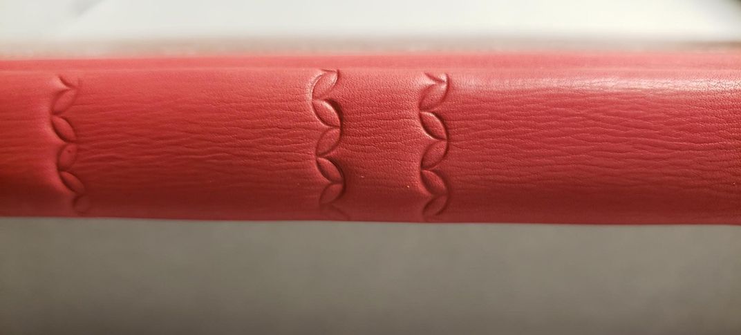 Close up view of a restored red leather binding, stamped with a petal design.Close up view of a restored red leather binding, stamped with a petal design.