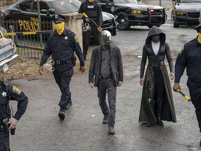 In a scene from the HBO series, Tulsa’s masked police force prepares for a raid. Detective Wade Tillman (known as “Looking Glass”) is played by Tim Blake Nelson. Detective Angela Abar (known as “Sister Night”) is played by Regina King (Mark Hill for HBO).