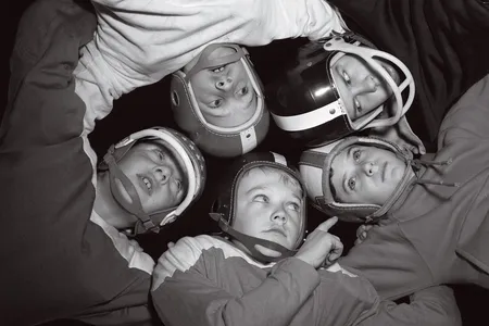 Young football players locked in a huddle in the 1960s, jealously guarding their strategy for the next play.