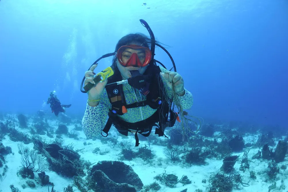 a female diver underwater holds up fishing line for the camera