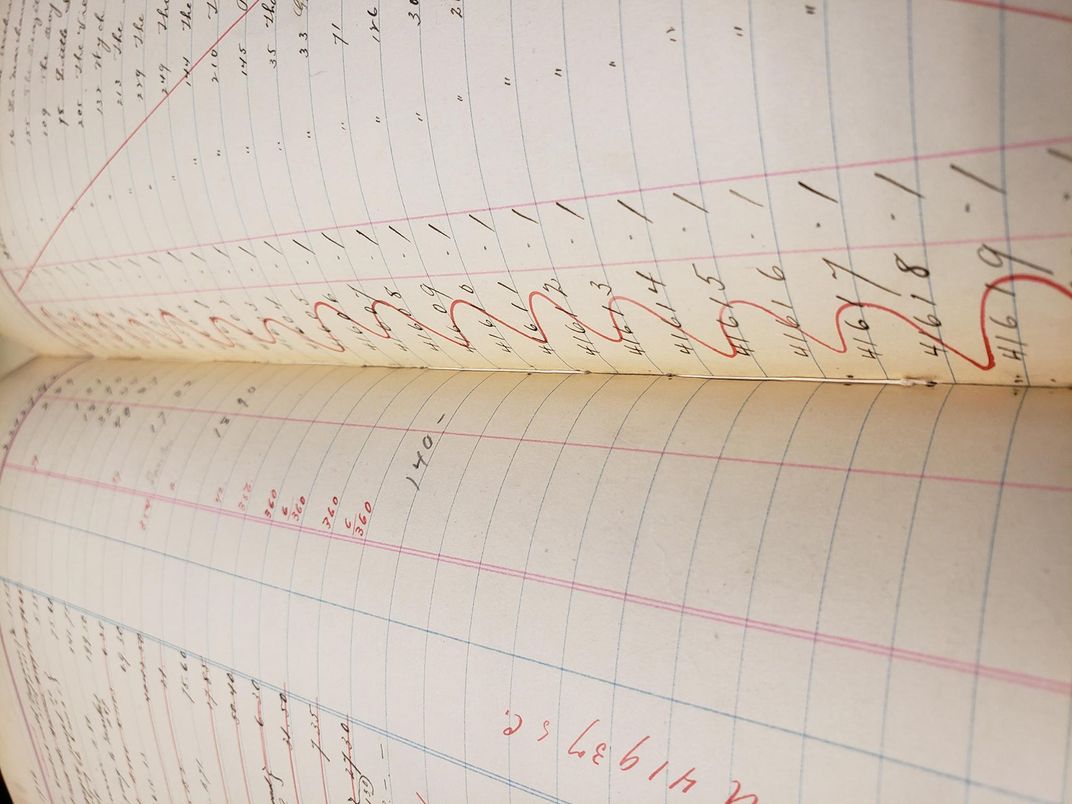 Close up interior view of volume with writing in red and black ink on lined pages and and thread showing from the newly sewn bindin.