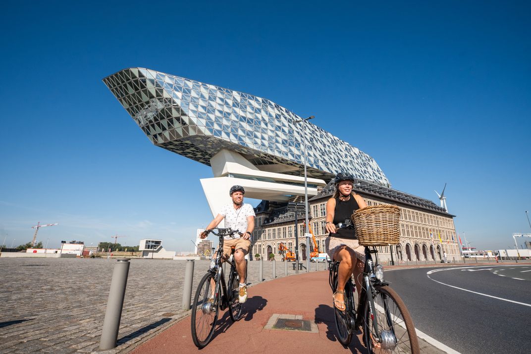 Cycling past Havenhuis, Zaha Hadid Architects, in Antwerp. Credit: VisitFlanders ©Visit Antwerp