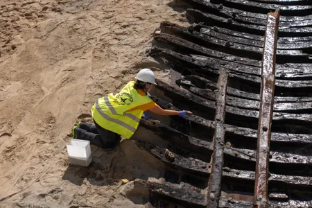 An archaeologist keeps the ship's delicate frame moist to prevent decay