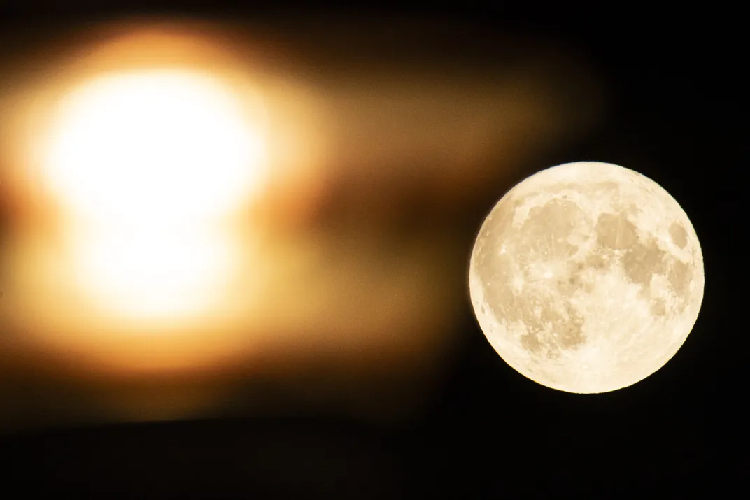 Strawberry full moon, behind city lights, rises in Eindhoven, Netherlands