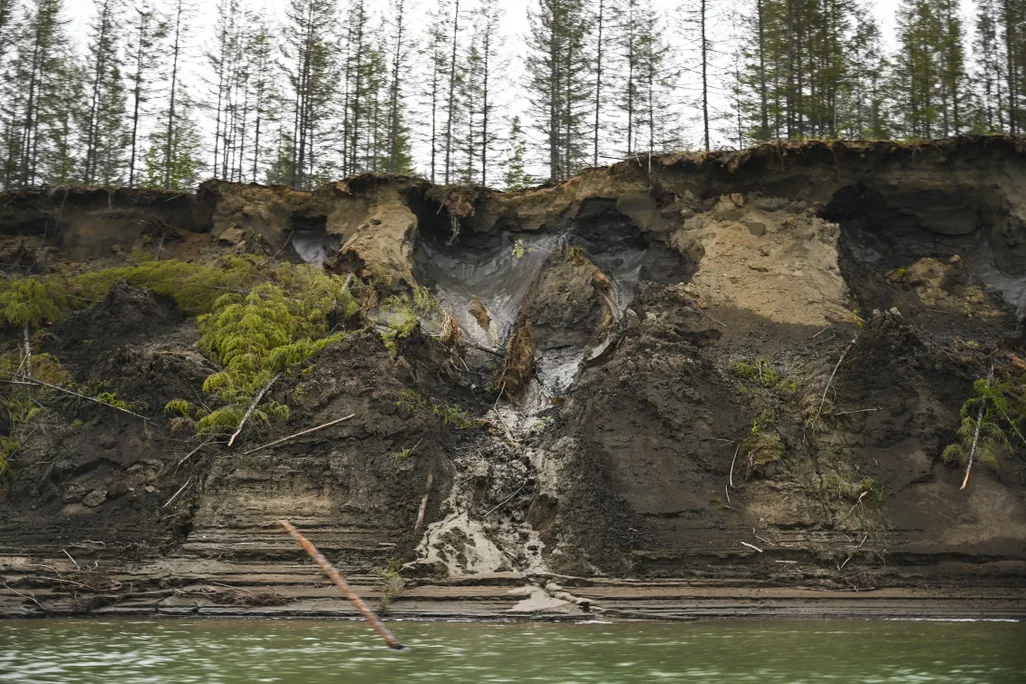 Permafrost melts down a cliff side above a river