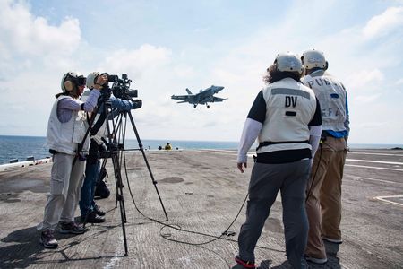 As an F/A-18 comes in for a trap, the STEM in 30 crew films operations on the Dwight D. Eisenhower flight deck.
