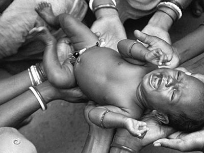 newborn held by relatives and neighbors