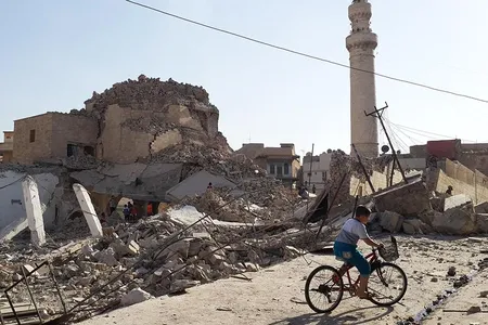A bicyclist rides by the destroyed old mosque and tomb of  Nabi Jerjis, also known as Saint George, in central Mosul in July 2014.