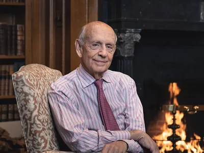 The cover of the book, Reading the Constitution, features Justice Stephen Breyer sitting in front of a blazing fire.