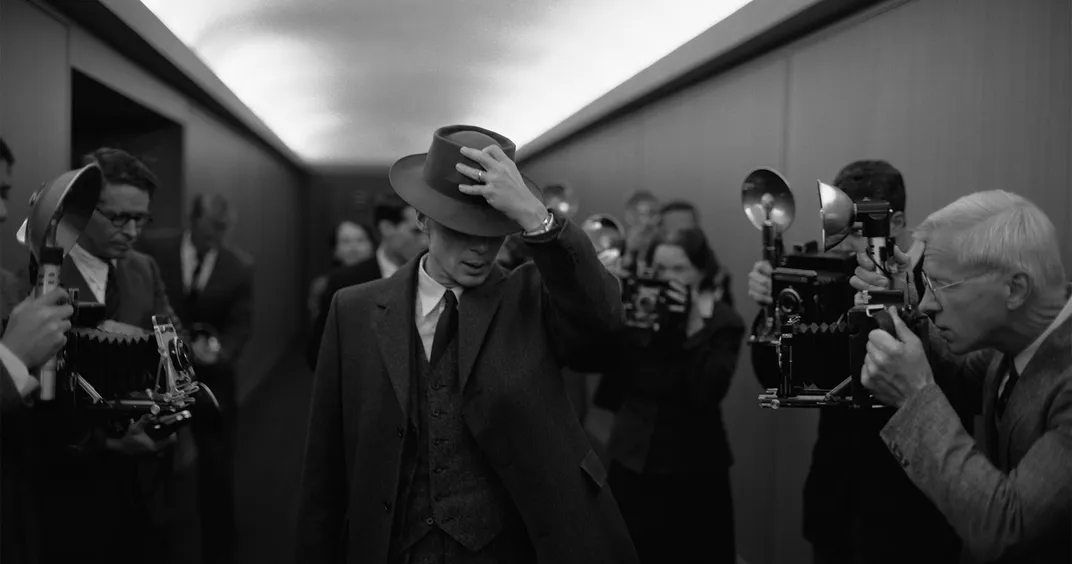 Cillian Murphy, as J. Robert Oppenheimer, walks through a crowd of photographers