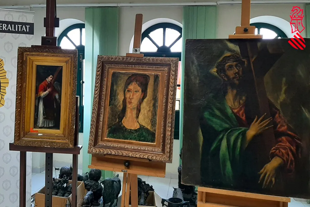 Three paintings on stands next to an official police logo on the wall behind them