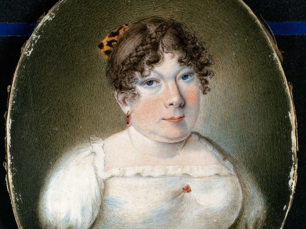 A miniature portrait of a white woman with curled brown hair in a white empress dress with a blue ribbon; her arms end below the shoulder, where her dress is pinned