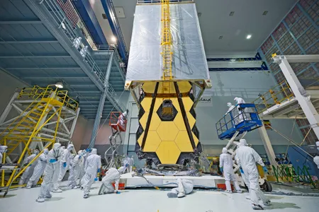 NASA technicians and engineers place a tent over the folded-up James Webb Space Telescope to protect it from dust and dirt once it leaves the "clean room" and proceeds to acoustic and vibrational testing.