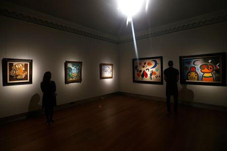 Two Christie's employees look at paintings set to be auctioned off in the Art of the Surreal sale.