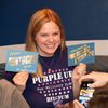 Woman smiling holds up two postcards