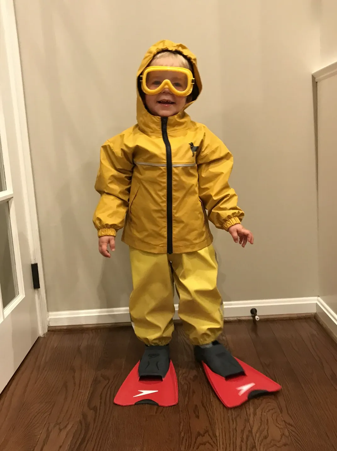 Young boy dresses up in raincoat, flippers, and goggles as part of dramatic play to mimic sea lion adaptations