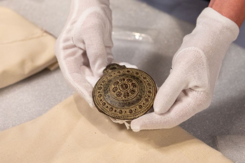 Gloved hands holding a medallion