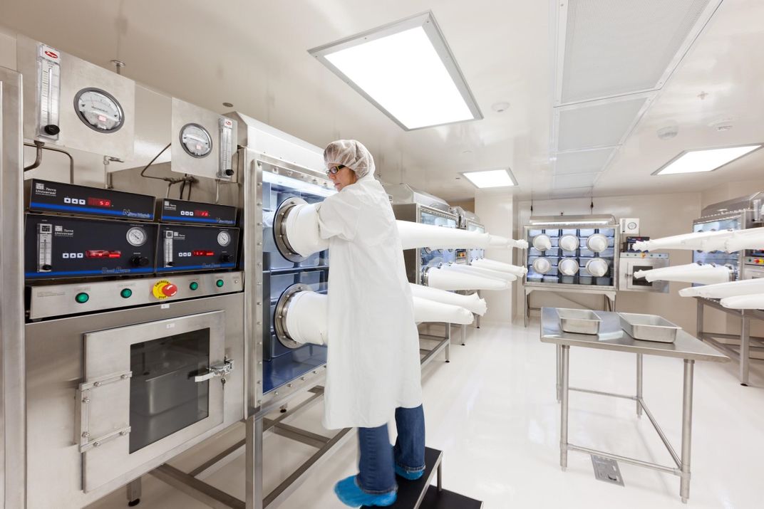 A scientist with her hands in a container.