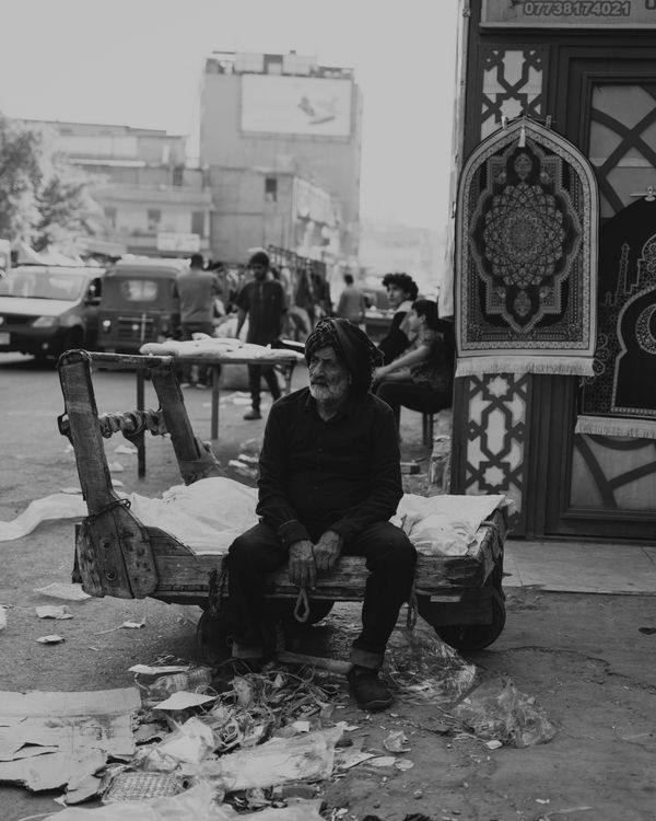 Old man sitting on a wooden wheelbarrow in Iraq thumbnail