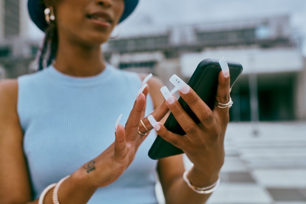 A woman with very long nails using a smartphone