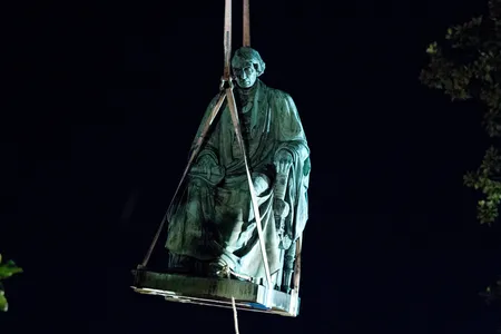 Workers use a crane to lift the monument dedicated to U.S. Supreme Court Chief Justice Roger Brooke Taney from outside Maryland State House, in Annapolis, Maryland, early Friday morning.