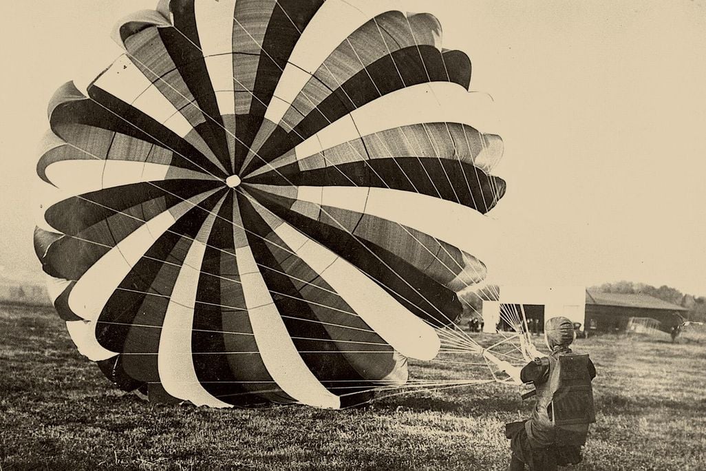 A woman holding the strings to a parachute canopy, having just landed