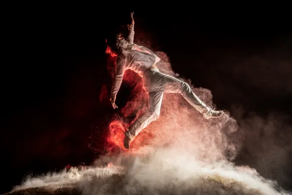 A lone athlete bursts upward, racing the rising cloud of dust below him. thumbnail