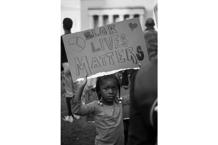 In a photograph by Devin Allen, a young girl holds a sign at a protest in Baltimore.
