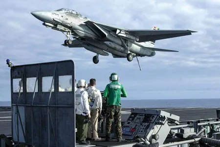 In January 2001, the Landing Signal Officer and other crew on the platform are only a few of the thousands supporting the mission to get this F-14 Tomcat safely aboard the USS Abraham Lincoln.
