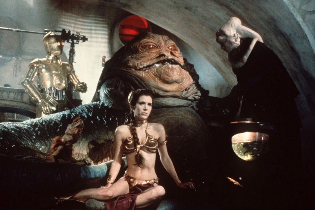 Woman wearing a gold bikini in front of a large slug-like creature