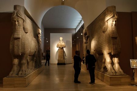 People look at ancient Assyrian human-headed winged bull statues at the Iraqi National Museum in Baghdad March 8, 2015.