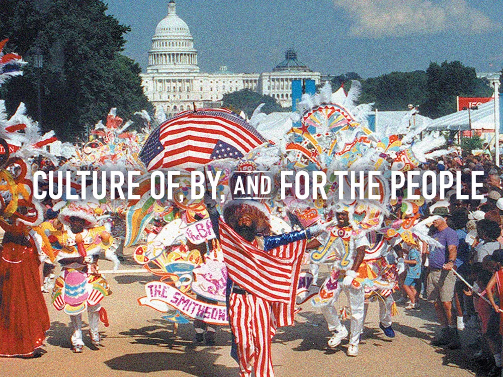 A vibrant parade on the National Mall with participants in colorful costumes, carrying flags and banners, in front of the United States Capitol building. Text is overlaid on the image that reads: Culture Of, By, and For the People