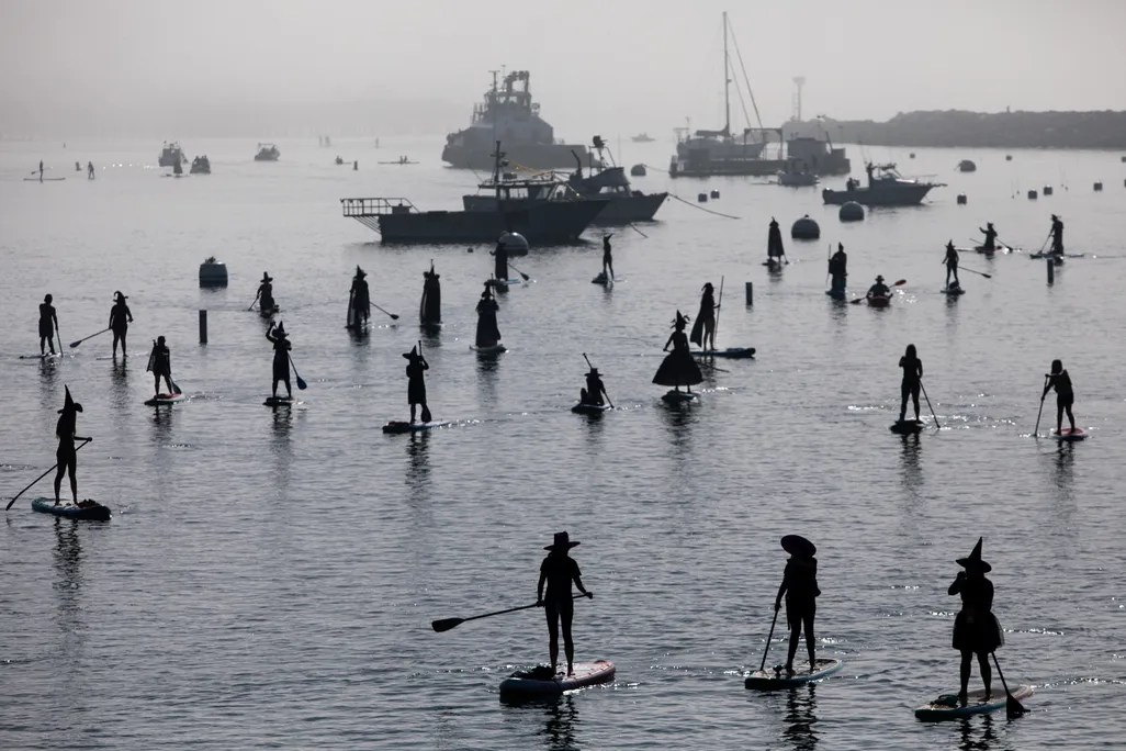 Silhouettes of people dressing as witches on standup paddleboards