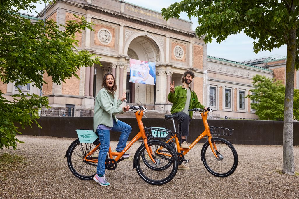 A woman and a man posing for a photo astride bikes