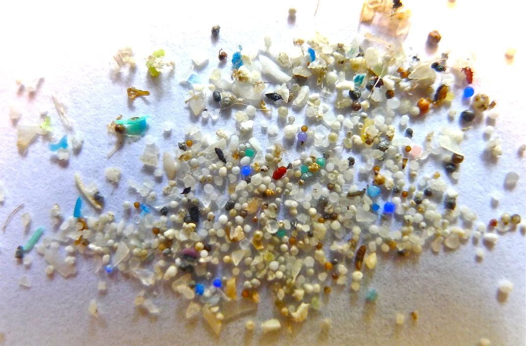 A variety of small plastic bits, many round, in a variety of colors, spread before a white surface