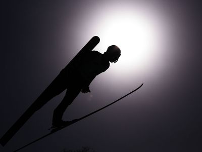 A ski jumper flashes a V.