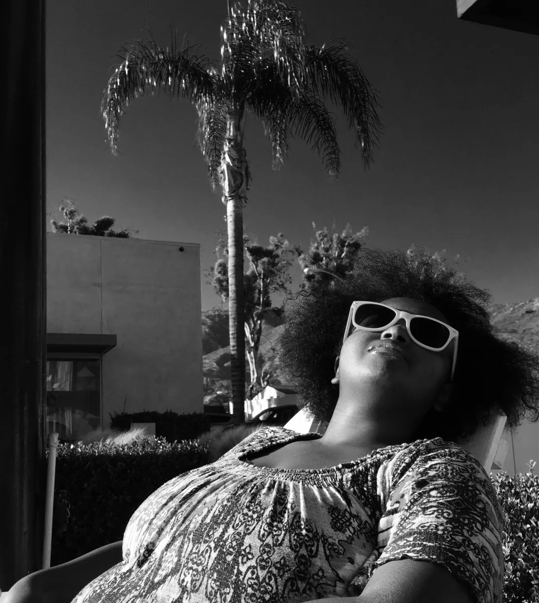 A black woman sunbathes in a chair